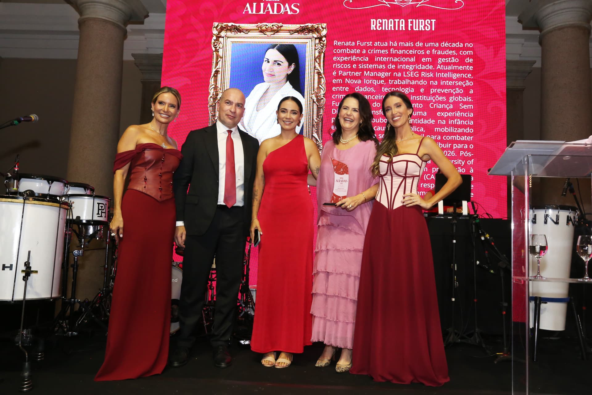 Momento de homenagem no palco do Prêmio Aliadas 2026, com a trajetória da homenageada apresentada no painel